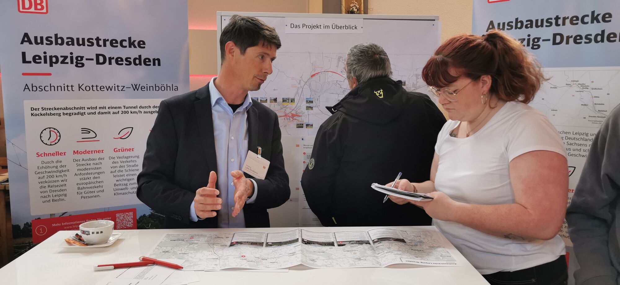 Zwei Personen stehen auf einer Informationsveranstaltung und befinden sich im fachlichen Austausch.