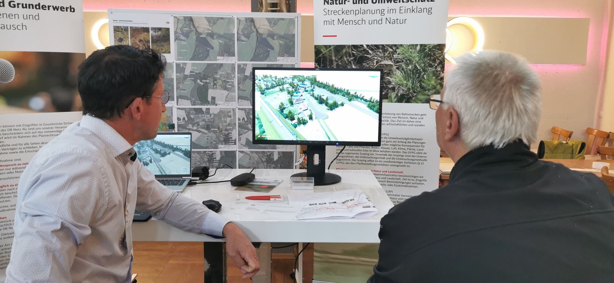 Zwei Personen schauen auf einen Monitor auf einer Informationsveranstaltung.