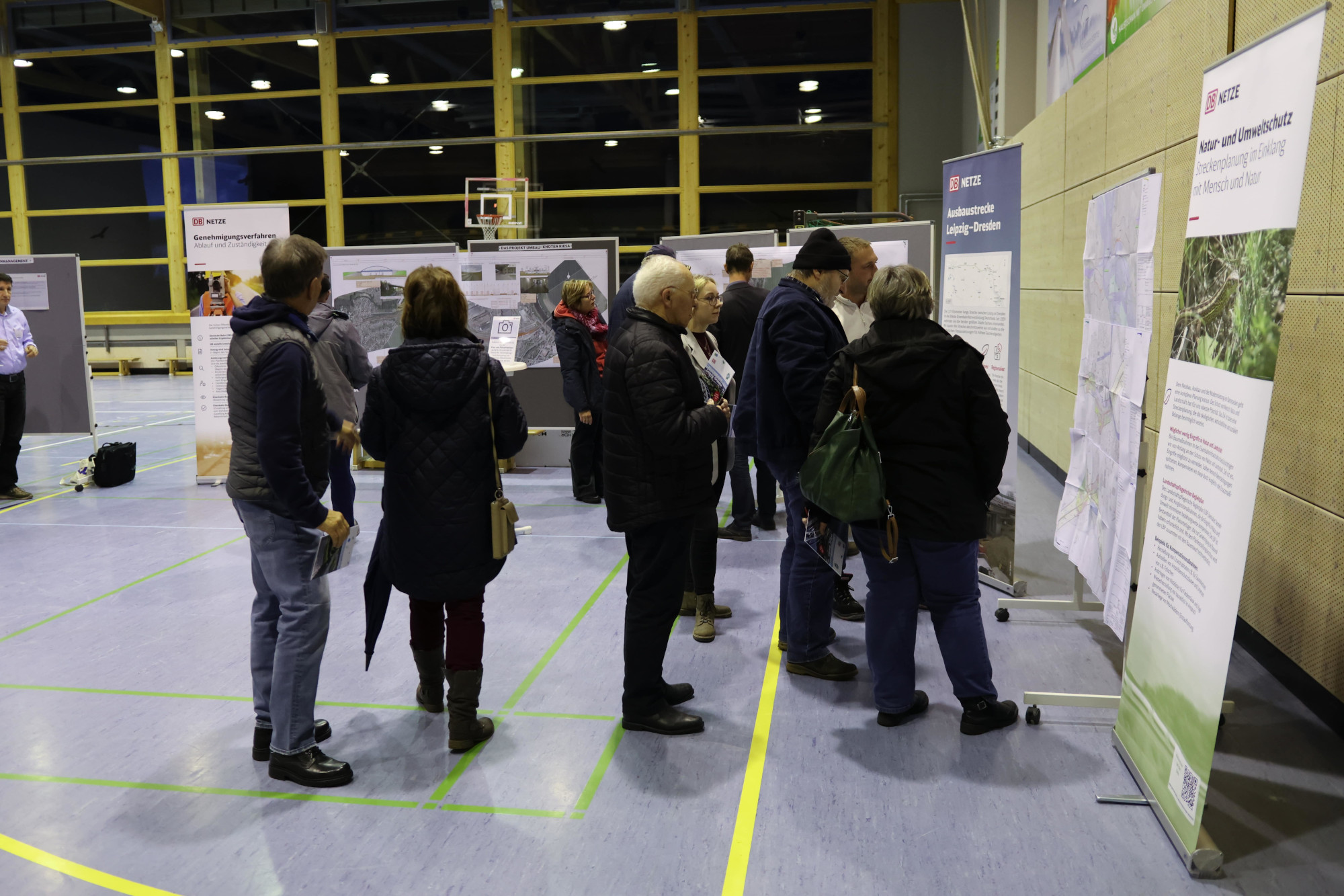 Eine Gruppe von Menschen steht vor Pinnwänden und Roll-Ups.